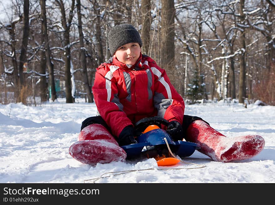 The Boy Sitting On A Sledge In Red Valenki.