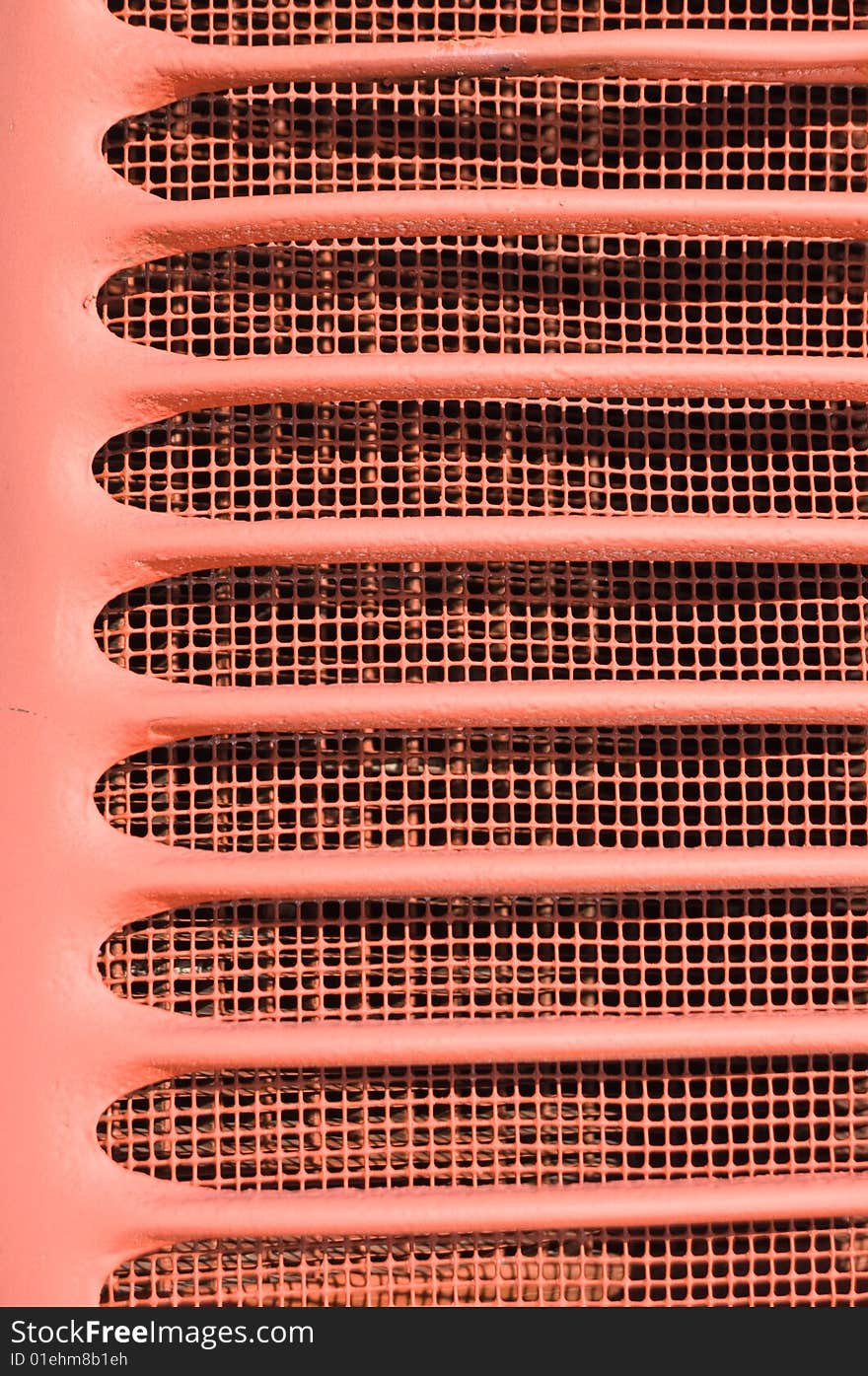 Red grill fins closeup from front of old vintage tractor.  Painted red stamped steel. Red grill fins closeup from front of old vintage tractor.  Painted red stamped steel.