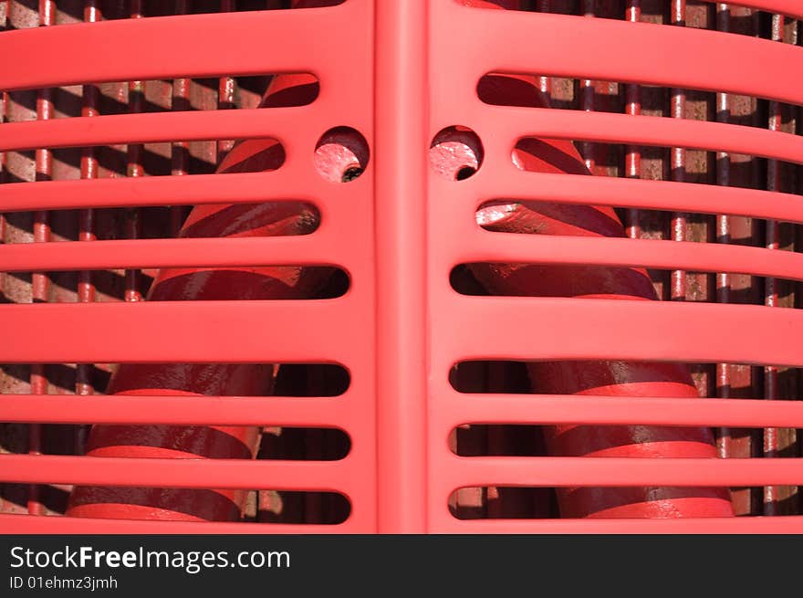 Red grill fins closeup from front of old vintage tractor. Painted red stamped steel. A vague face within form. Red grill fins closeup from front of old vintage tractor. Painted red stamped steel. A vague face within form.