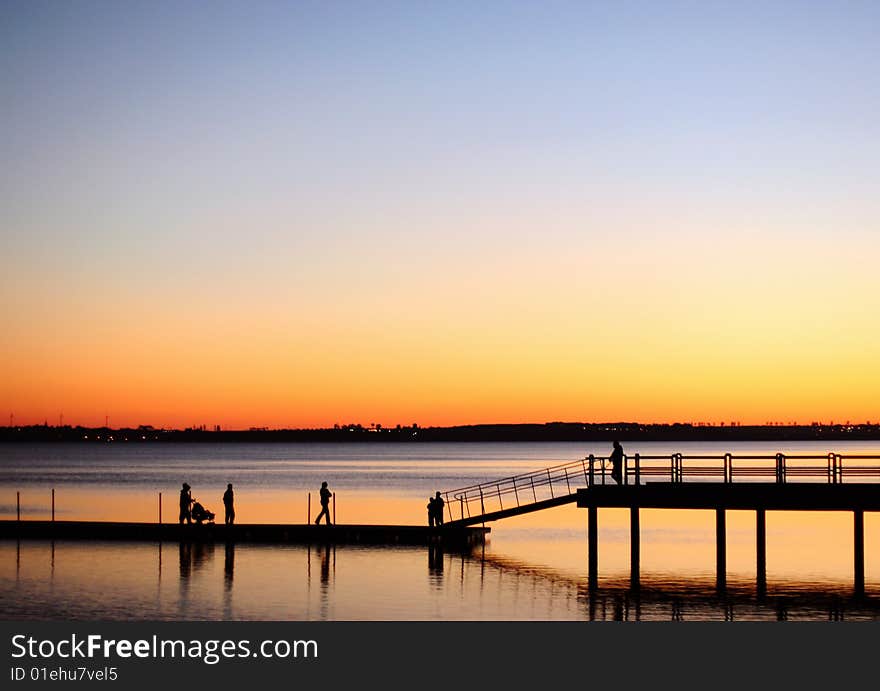 A view of silhouetted people walking on a pier