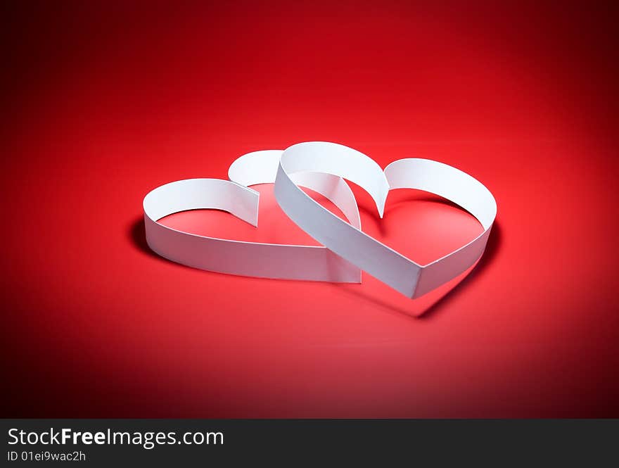 Intertwining of two hearts with center spot light, on red background. Focus on a center. Intertwining of two hearts with center spot light, on red background. Focus on a center.