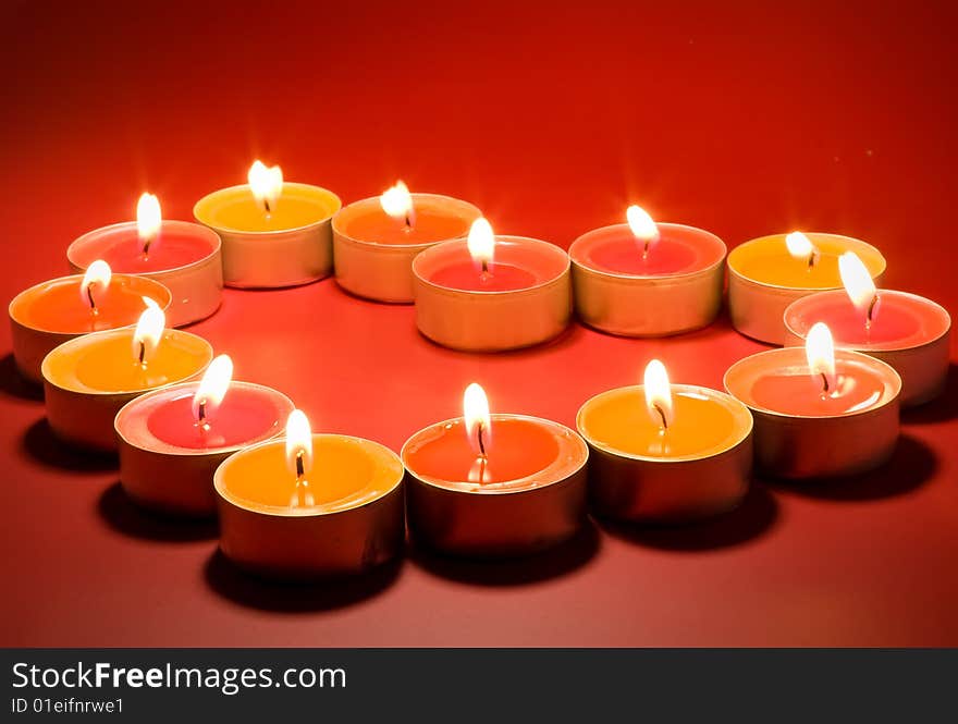 Small light candles, in heart form on a red background. Small light candles, in heart form on a red background.