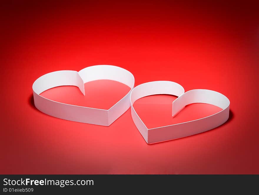 Intertwining of two hearts with center spot light, on red background. Focus on a center. Intertwining of two hearts with center spot light, on red background. Focus on a center.