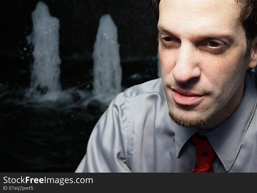 Businessman sitting by an abstract water fountain. Businessman sitting by an abstract water fountain