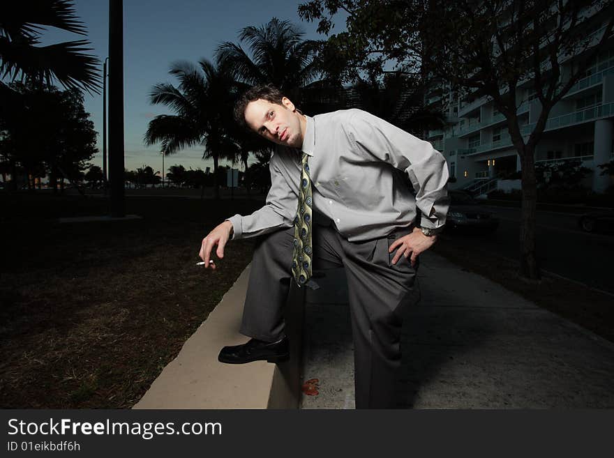 Businessman in an unusual pose while holding a cigarette in his hand. Businessman in an unusual pose while holding a cigarette in his hand