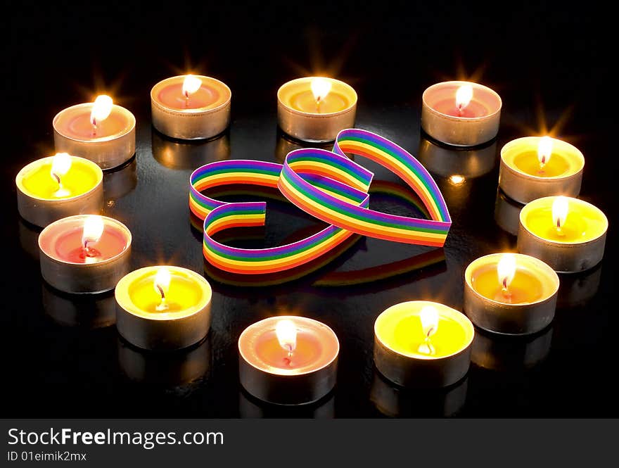 Two gay-colour  hearts, surrounded small candles light, on a black background. Two gay-colour  hearts, surrounded small candles light, on a black background.