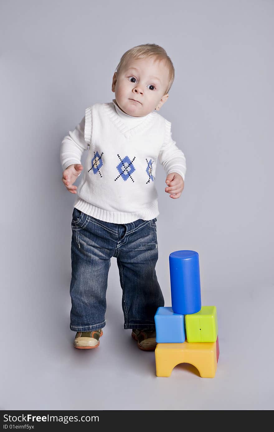 Little boy play with bricks in grey background