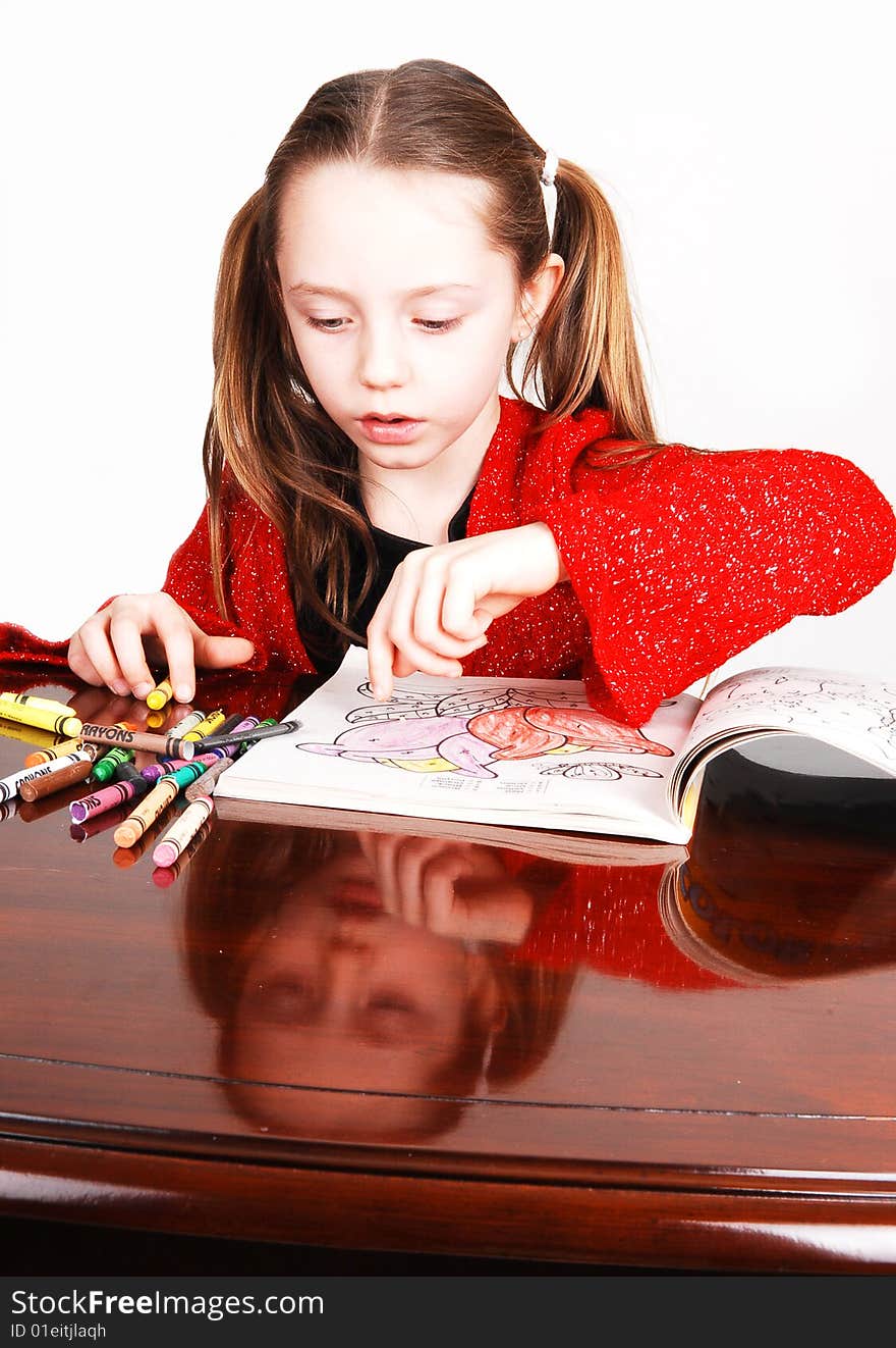 Little girl in a red sweeter sitting on the table and coloring an book
with crayons. Her face mirroring in the table. Little girl in a red sweeter sitting on the table and coloring an book
with crayons. Her face mirroring in the table.