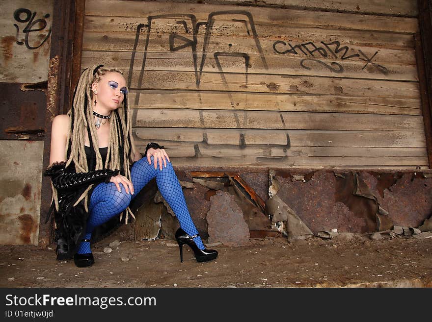 Young woman wearing punk clothing and makeup in deserted location