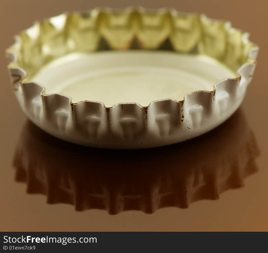 Metal beer cap on brown surface