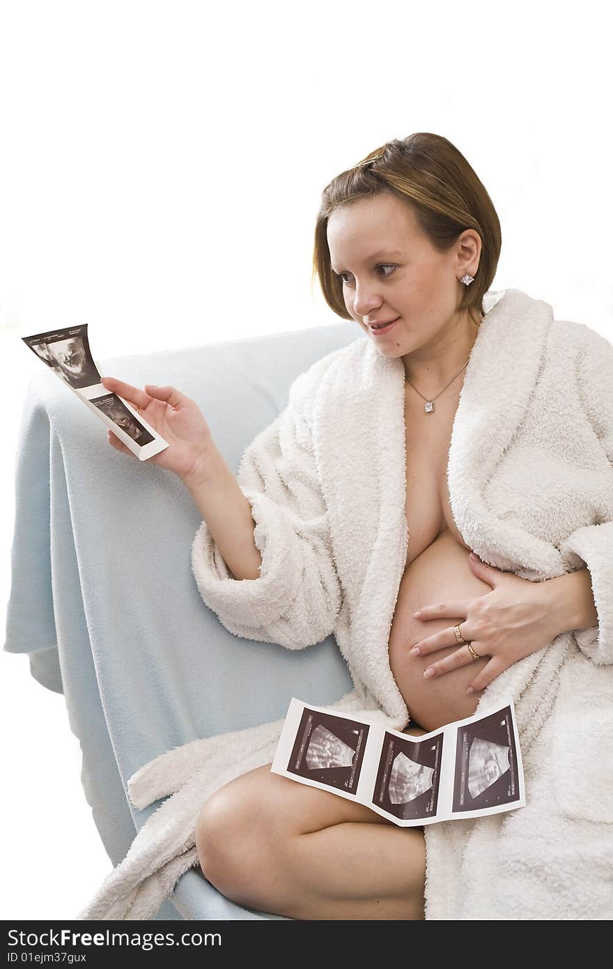 Young Pregnant woman looking on the ultrasonic sonogram in her hands. Young Pregnant woman looking on the ultrasonic sonogram in her hands