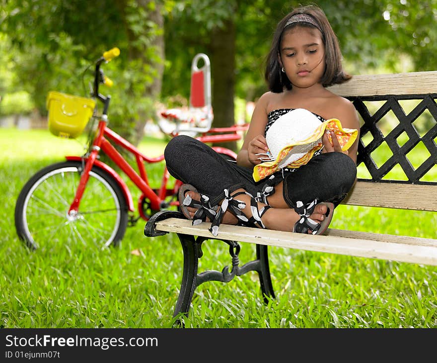 Asian kid of indian in a park sitting in a bench. Asian kid of indian in a park sitting in a bench