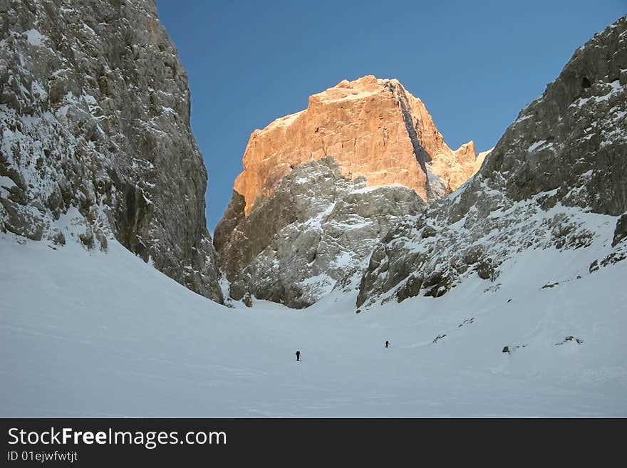 Idyllic winter mountain scene with mountaineers trudging through snow. Jalovec. Julian Alps, Triglav national park, Slovenija. Idyllic winter mountain scene with mountaineers trudging through snow. Jalovec. Julian Alps, Triglav national park, Slovenija