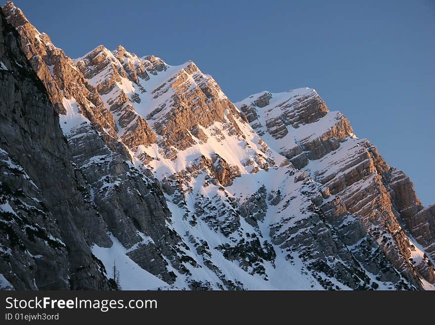 Idyllic winter mountain scene with azure sky over the snowcapped peak.Mountain peak Jalovec. Julian Alps, Triglav national park, Slovenija. Idyllic winter mountain scene with azure sky over the snowcapped peak.Mountain peak Jalovec. Julian Alps, Triglav national park, Slovenija