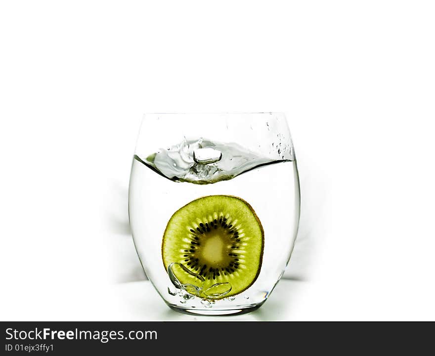 Kiwi fruit splashed into glass of water