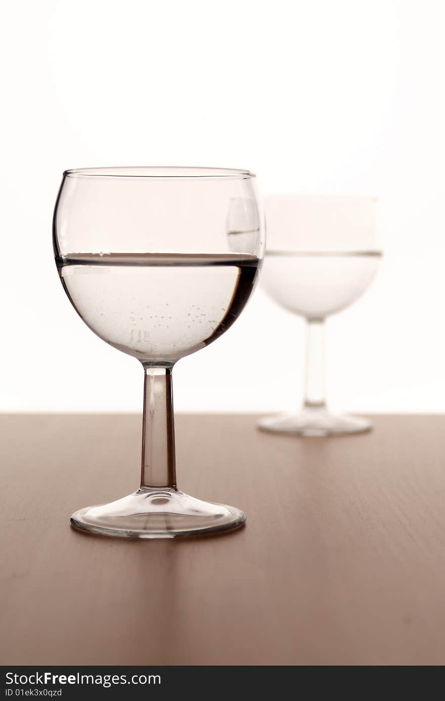 Two wine glasses in backlight on white contrast background