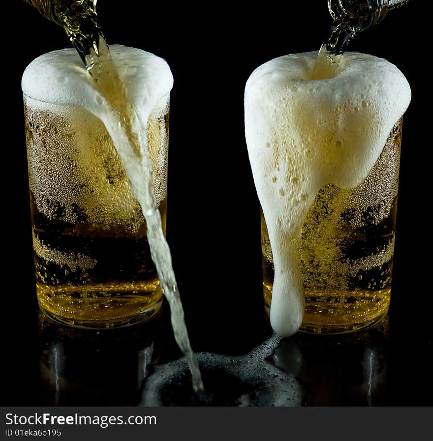 A glass of cold beer with foam on a black backgraund