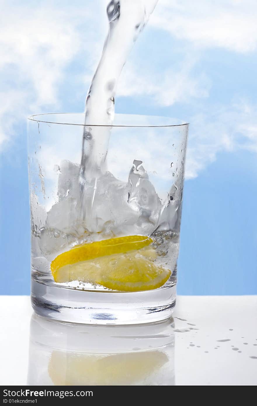 Glass of Water with Lemon on ice and sky background