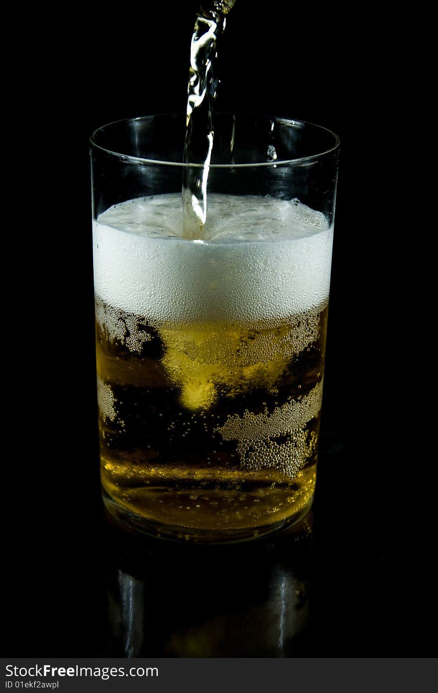 A glass of cold beer with foam on a black backgraund