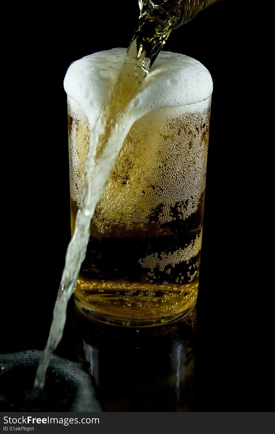 A glass of cold beer with foam on a black backgraund