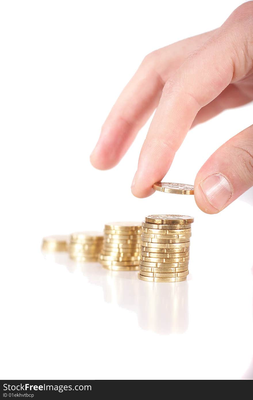 A hand is stacking up coins. Coins are mirrored. Isolated over white. Ideal Businesshot. A hand is stacking up coins. Coins are mirrored. Isolated over white. Ideal Businesshot.