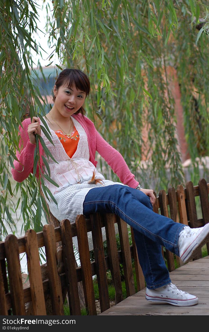 A  beautiful Young girl  sitting on the fence ,from china. A  beautiful Young girl  sitting on the fence ,from china