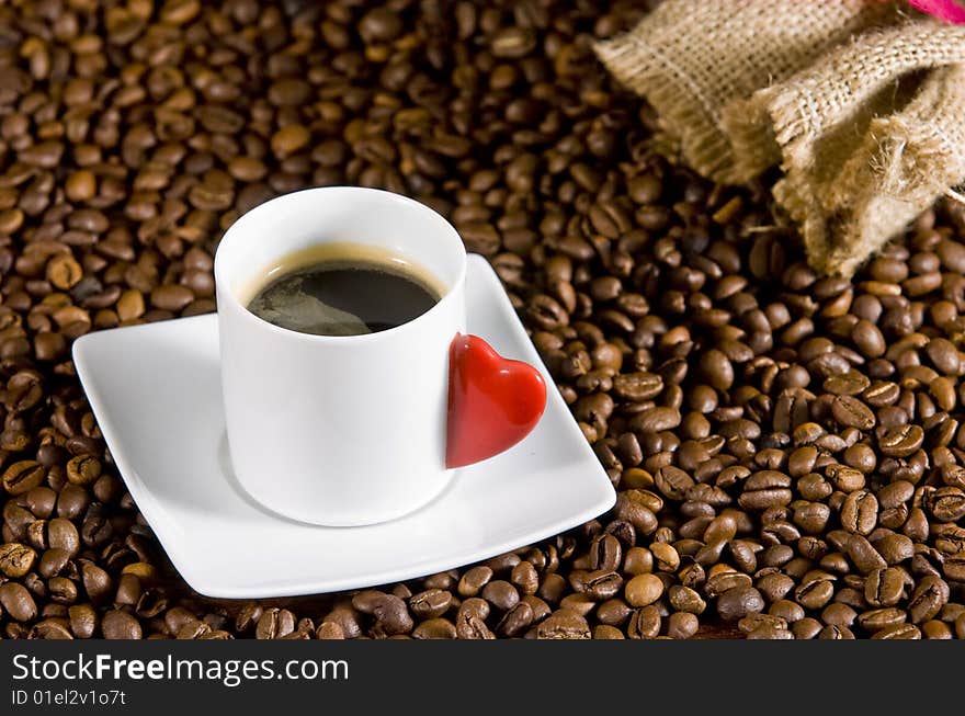 Espresso served on heart shaped cup on coffee beans