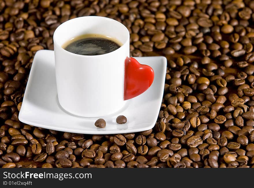 Espresso served on heart shaped cup on coffee beans