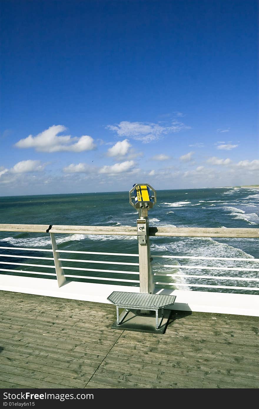 Photo of a telescope on a boardwalk overlooking the sea. Photo of a telescope on a boardwalk overlooking the sea.