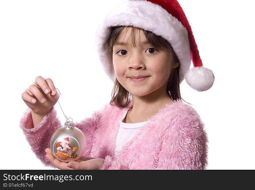 A girl with a santa hat holds a small roundchristmas ornament. A girl with a santa hat holds a small roundchristmas ornament.