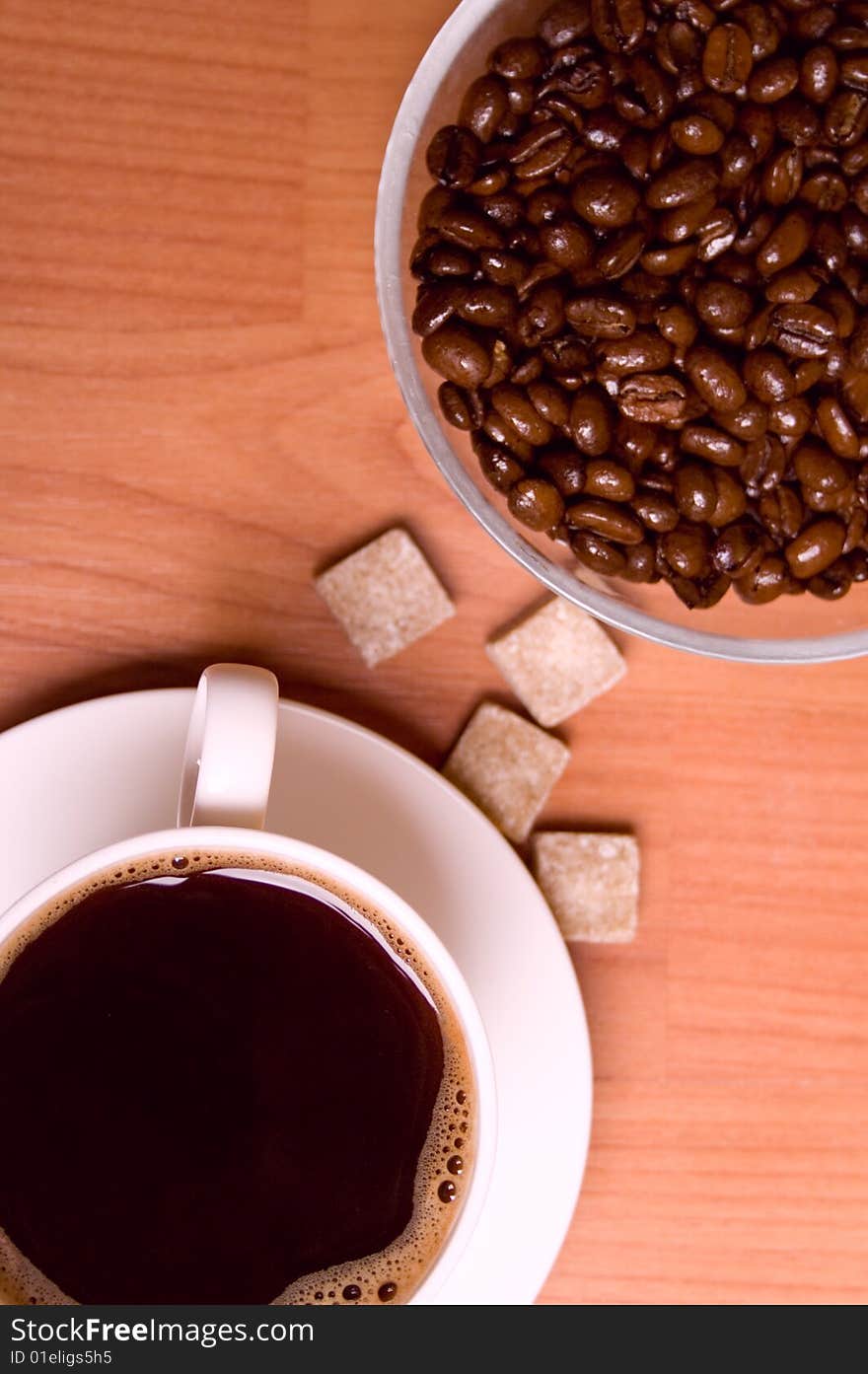 Cup of coffee, beans and sugar on wooden table