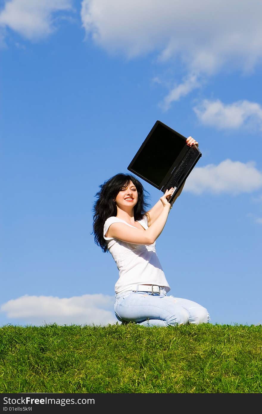 Pretty woman with laptop on the green grass