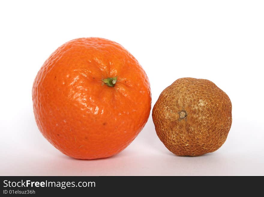 A fresh and a desiccated tangerine alongside each other. A fresh and a desiccated tangerine alongside each other