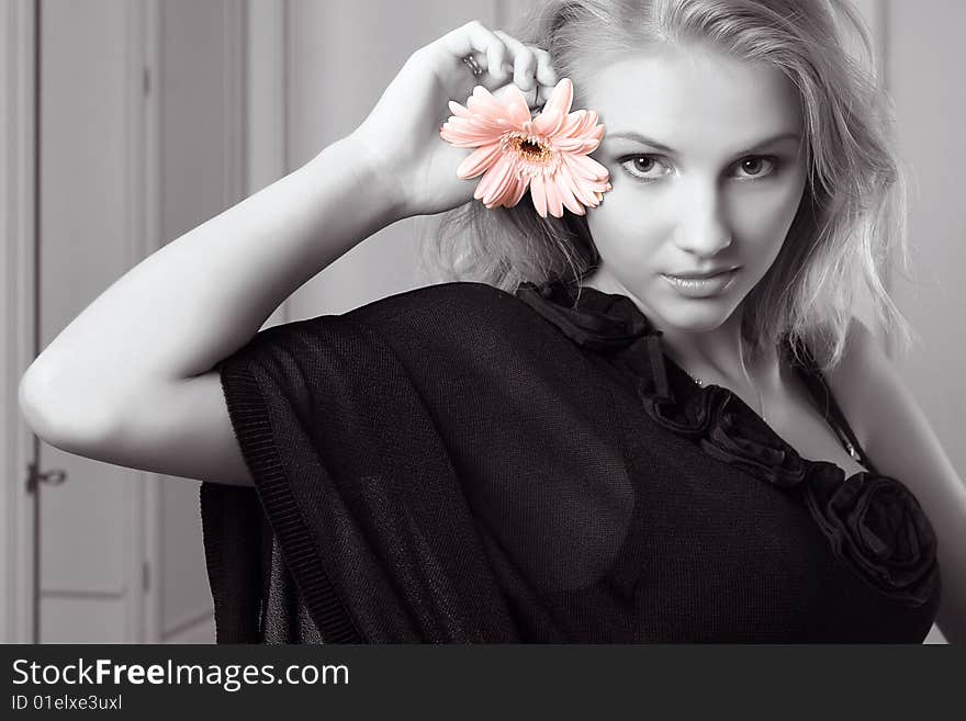 Attractive young woman holding gerbera and looking at camera