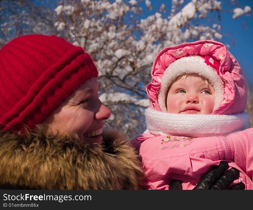 Mother with daughter on background of the snow-clad branch