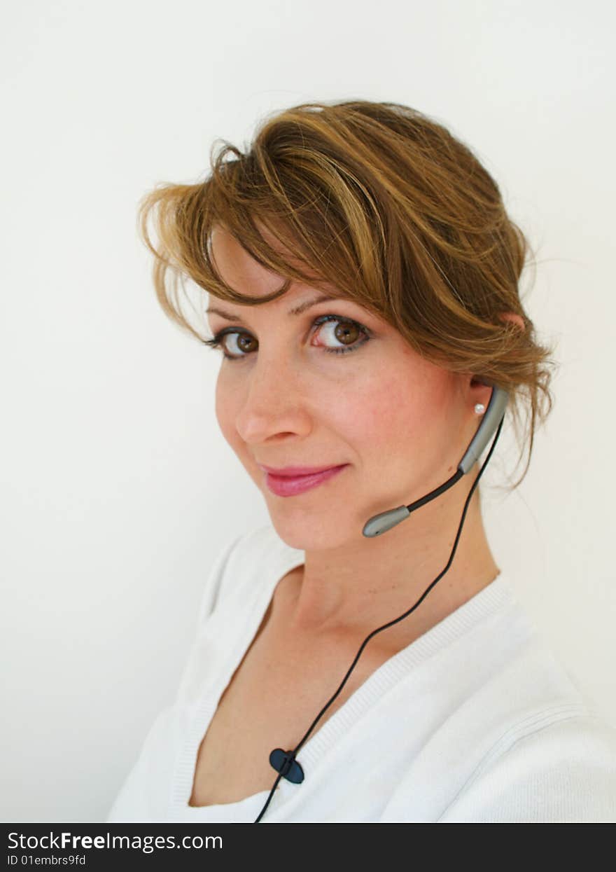 Business professional,woman, brunette smiling  wearing white, and a headset. Business professional,woman, brunette smiling  wearing white, and a headset.