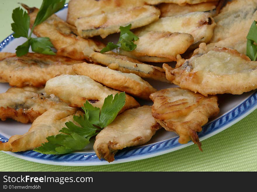 Breaded deep fried zucchini and anchovies close up