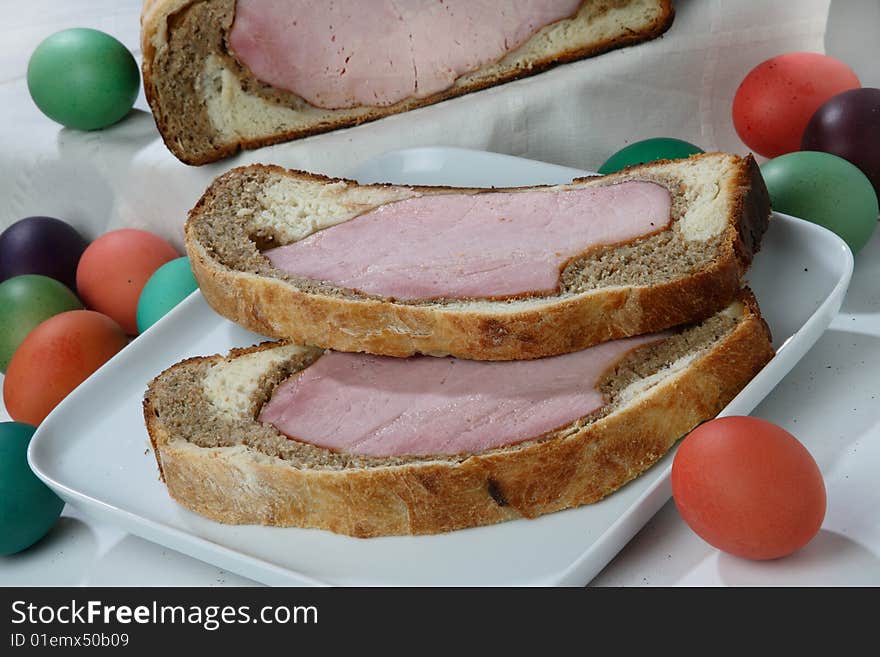 Easter ham on bread with colored eggs on plate