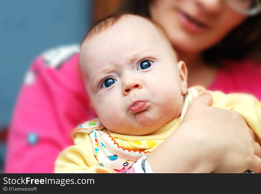 Little 4-month boy pouts his lips in mama's hands