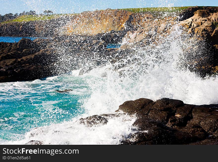 Waves hitting rocky shore on a sunny day