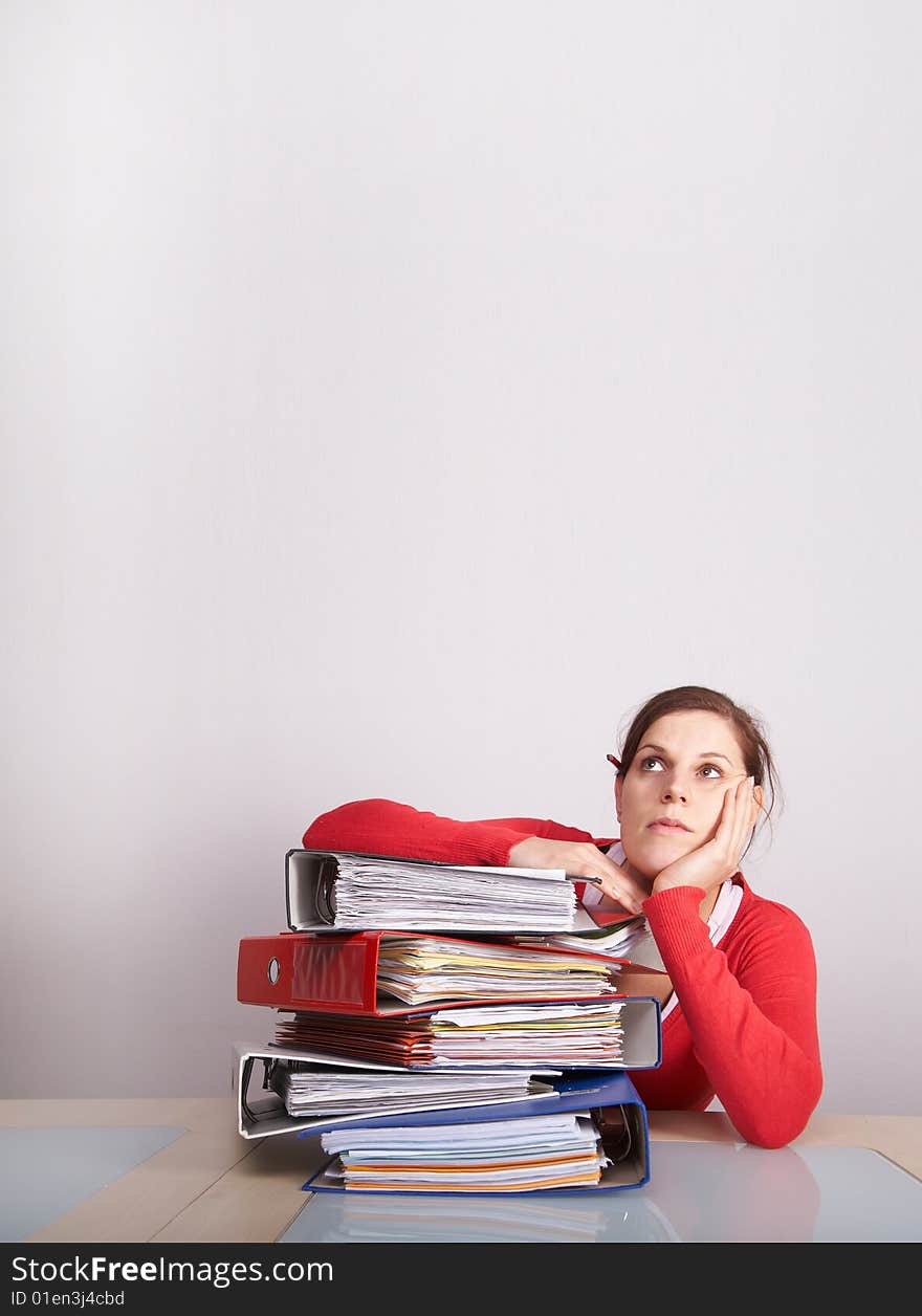 A young and beautiful female worker is stressed with a lot of paperwork in front of her and a pencil in her hair. A lot of copyspace. A young and beautiful female worker is stressed with a lot of paperwork in front of her and a pencil in her hair. A lot of copyspace.