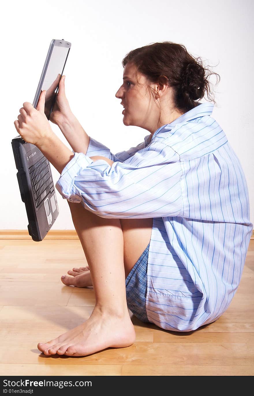 A young woman at home with her laptop sitting on the floor in her new appartment. She seems to be very frustrated. A young woman at home with her laptop sitting on the floor in her new appartment. She seems to be very frustrated.