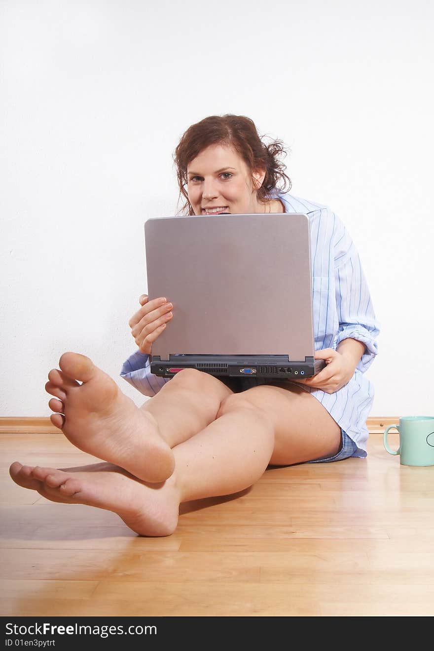 A young woman with a laptop on the floor at home. A young woman with a laptop on the floor at home.