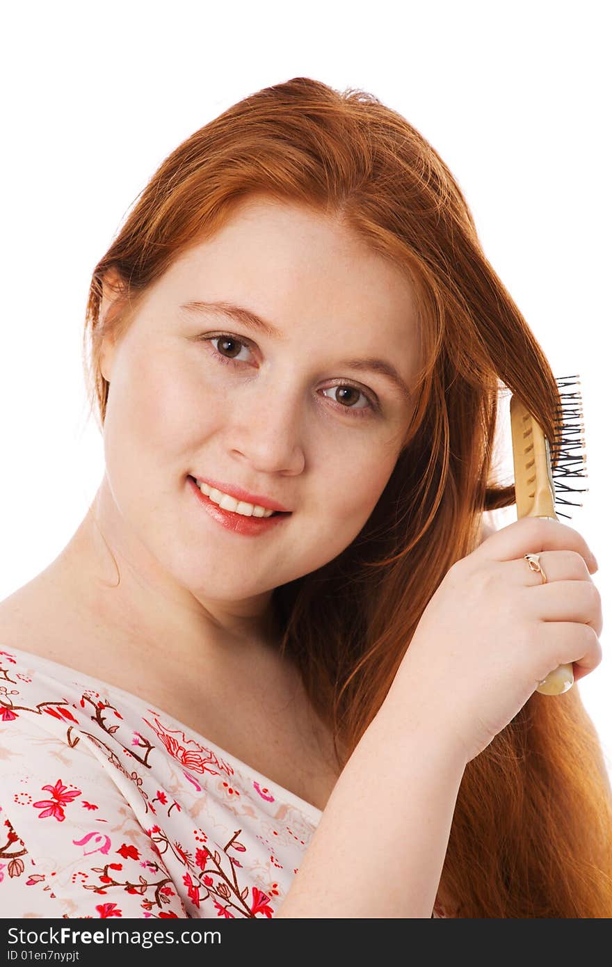 The young beautiful woman combs long red hair, smiles, on a white background