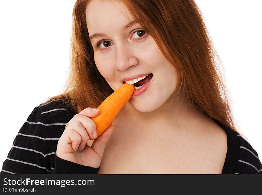 The young beautiful woman with long red hair eats a carrot. The young beautiful woman with long red hair eats a carrot