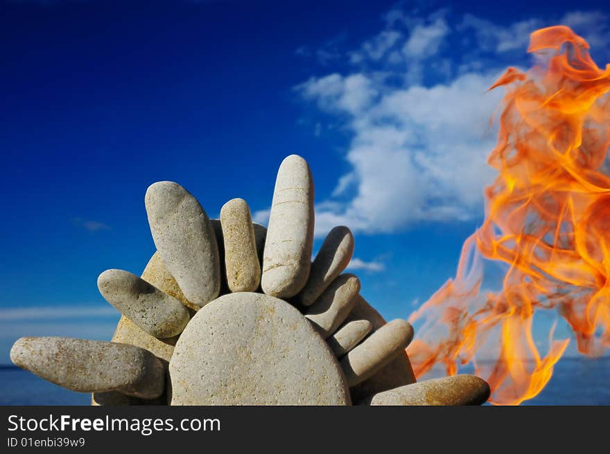 Fire and the stone sun on a beach at midday. Fire and the stone sun on a beach at midday