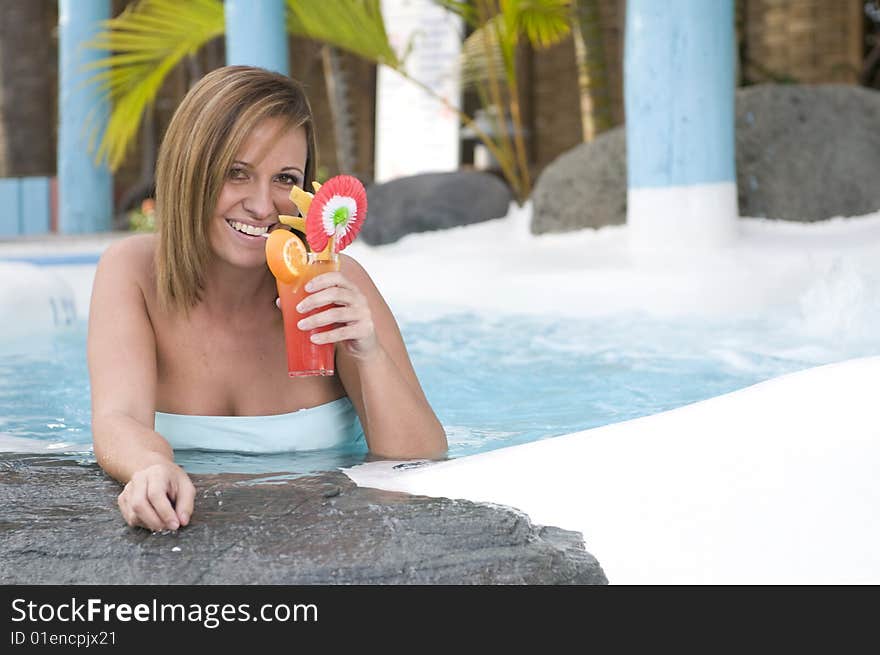 Beautiful woman with cocktail in a swimming pool