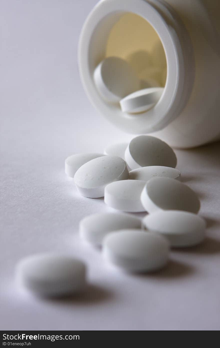 Picture of a plastic bottle with a lot of white pills on the table. Picture of a plastic bottle with a lot of white pills on the table