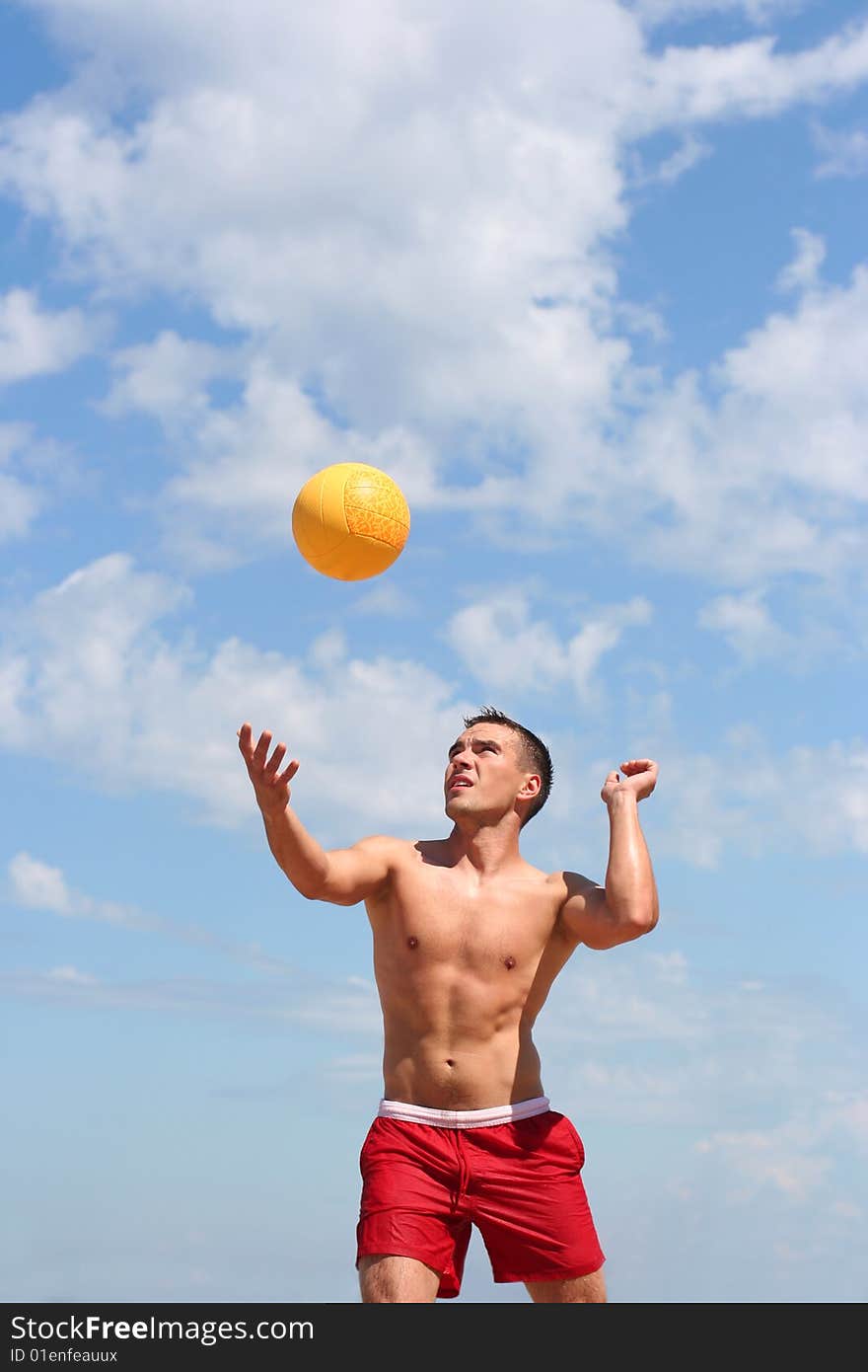 Athletic guy playing volley-ball on the beach