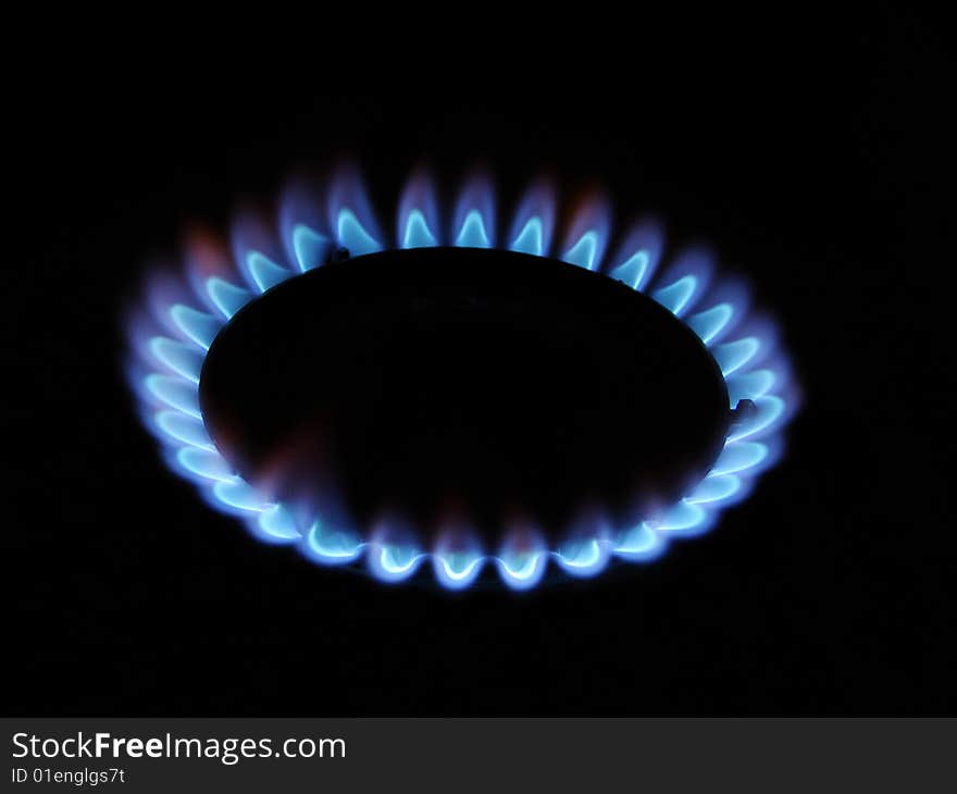 Blue flame of gas over black background